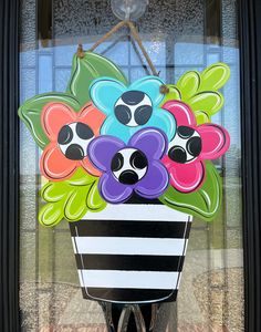 a flower pot with flowers painted on the side of it is hanging from a door