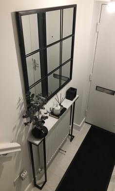 a black and white hallway with a mirror, planter and radiator on the wall