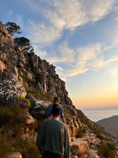 two people standing on the side of a mountain