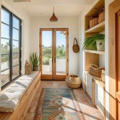 a room with a bench, potted plant and glass doors leading to the outside