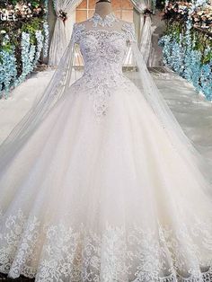 a white wedding dress on display in front of flowers