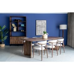 a blue dining room with white chairs and a wooden table in front of a bookshelf