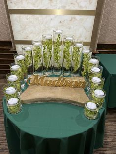 a table topped with lots of glasses filled with green plants