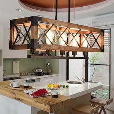 a kitchen with a wooden table and some lights hanging from it's ceiling over the island