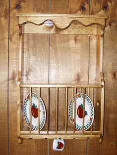 a wooden shelf with two plates and an apple plate holder on the top, hanging from it's side