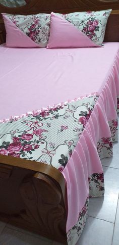 a bed with pink bedspread and matching pillow cases on top of it's headboard