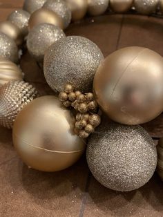 silver and gold ornaments are arranged on a brown table top, with beaded balls around the edges