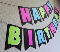 a happy birthday banner hanging on the wall with neon colored letters and buntings