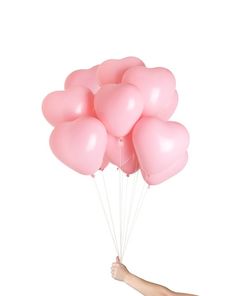 a hand holding a bunch of pink balloons