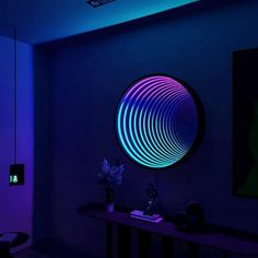 a room with blue and purple lighting on the walls, an abstract art piece in the corner