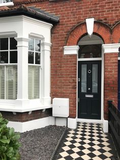 a black and white checkered floor in front of a brick building with two windows