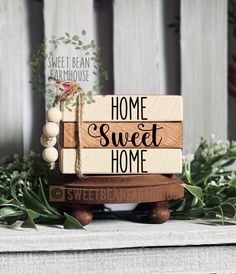 a wooden sign that says welcome to our home on top of a table with greenery