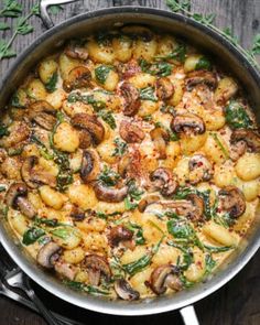 a pan filled with pasta and mushrooms on top of a wooden table