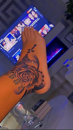 a person with a rose tattoo on their arm next to a computer monitor and keyboard