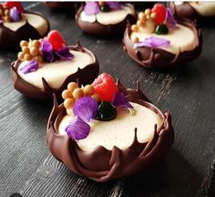 chocolate desserts decorated with flowers and leaves on a wooden table, ready to be eaten