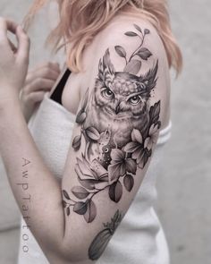 a woman with an owl and flowers tattoo on her arm