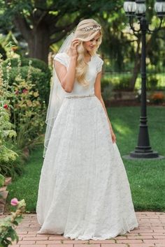 a woman in a wedding dress standing on a brick walkway with a light pole behind her