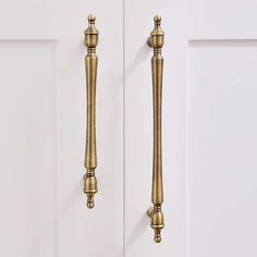 two golden handles on the front door of a white cabinet with gold knobs and pulls