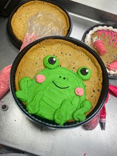 there is a cake in the shape of a frog and two other cakes on the table