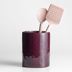 two kitchen utensils sticking out of a purple cup