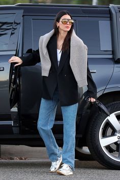 a woman is standing in front of a black suv with her hand on the door handle