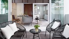 a living room filled with lots of furniture next to a patio covered in white pillows