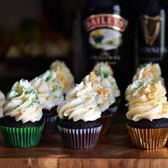 cupcakes with white frosting and green sprinkles next to a bottle of booze