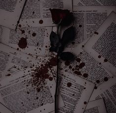 a single rose sitting on top of an open book with blood splatters all over it