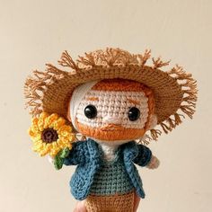 a crocheted doll holding a sunflower in its hand and wearing a straw hat