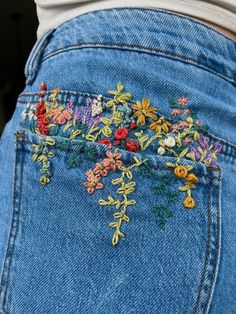 the back of a woman's jeans with embroidered flowers on it