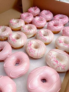 a box filled with pink frosted donuts and sprinkles on them