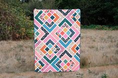 a colorful quilt sitting in the middle of a field