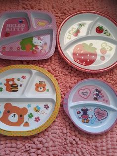 four children's plates with animals and hearts on them sitting on a pink blanket