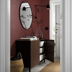 a room with red walls and a white cabinet in the corner, mirror on the wall