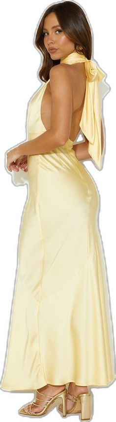 a woman in a yellow dress is standing with her back to the camera and she has one hand on her hip