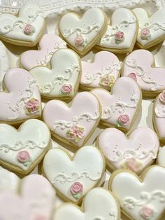 some heart shaped cookies are sitting on a plate with pink and white frosted icing