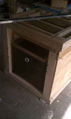 an unfinished wooden cabinet with glass top in the process of being built by someone's hand