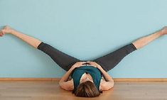 a woman is doing a handstand on the floor in front of a blue wall