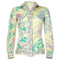 This late 1960s pastel toned silk blouse by Emilio Pucci is feminine, chic and in lovely vintage condition. The soft silk fabric has a abstracted floral design synonymous with its creator in soft shades of lemon, sugar pink, jade green and lilac. As with all of his pieces, the "Emilio" signature is incorporated subtly into the surface pattern. There is a central button stand hosting 6 silk covered buttons. The blouse can be fastened right up to the neck or be worn open as desired. The long sleev Pucci 1960s, Pucci Vintage, Pink Jade, Lemon Sugar, Feminine Chic, Yellow Silk, Floral Print Blouses, Gianni Versace, Emilio Pucci