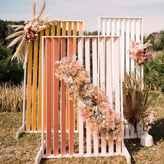 an assortment of flowers and plants are on display in front of a wooden fence with orange stripes