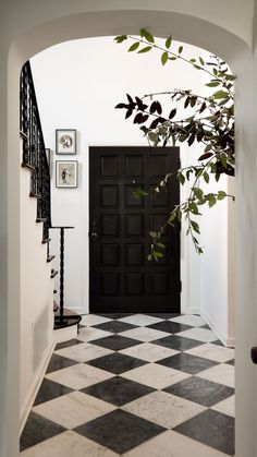 a black and white checkered floor with a door in the center is seen through an archway