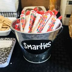 a bucket full of smarties sitting on top of a table next to other snacks