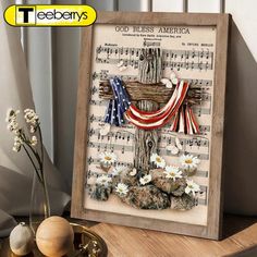 a wooden frame with an american flag and flowers on it, next to a vase