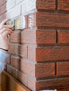 a person is painting a brick wall with white paint on the outside and red bricks on the inside