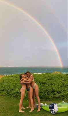 two women hugging each other in front of the ocean with a rainbow in the background