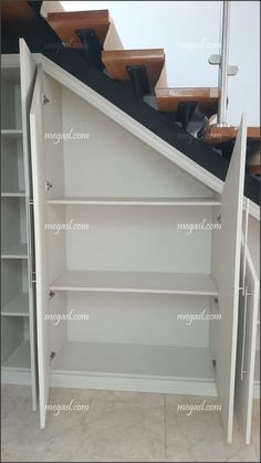 an open book shelf in the corner of a room with stairs leading up to it