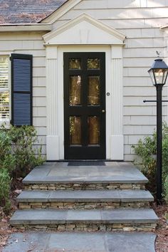 a black front door on a house with steps leading up to it and a lamp post