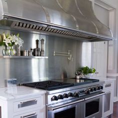 a stainless steel stove top oven sitting inside of a kitchen next to white cabinets and drawers