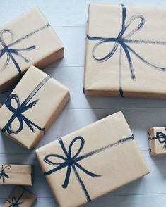 four wrapped presents are sitting on the floor next to each other, tied with blue ribbon