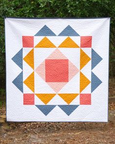 a quilted wall hanging in front of some trees